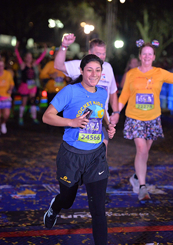 Angelina Mata, a senior in the College of Pharmacy and Pharmaceutical Sciences, crosses tje finish line of the Dopey Challenge at Disney World in Orlando, Florida, while wearing a Rocket Kids T-shirt.
