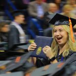Lindsey Shaffer excitedly raises her diploma holder as she walks back to her seat after receiving a bachelor of science degree in construction engineering technology during the afternoon fall commencement ceremony on Saturday, Dec. 16, in Savage Arena.