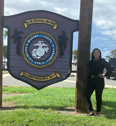 Photo of UToledo law student Kathryn Tucker posing next to a sign at Guantánamo Bay U.S. Naval Base in Cuba.