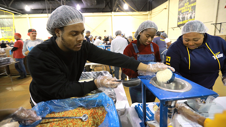 Volunteer Andre White, a senior studying psychology, scoops ingredients into a meal pack during Friday evening’s Feed My Starving Children Meal-packing event in the Health Education building gymnasium.