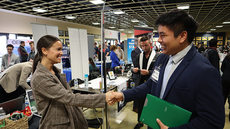 Kristian Mendoza, a senior studying marketing and management, networks with Tiranee Brunnet, senior recruiting manager with LeafHome, at the John B. and Lillian E. Neff College of Business and Innovation's Spring Job Fair on Friday in UToledo's Savage Arena.