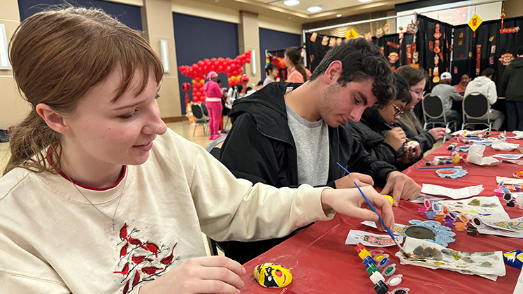 Ingrid Harmon, a junior studying exercise science, and Sameer Taweel, a junior studying biology, paint mini-Chinese opera masks.