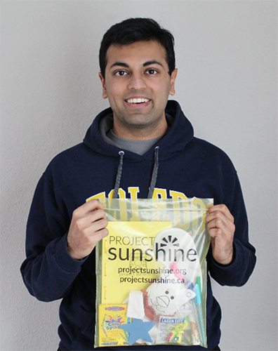 Photo of UToledo junior, Sajan Shah, holding a Project Sunshine activity kit.