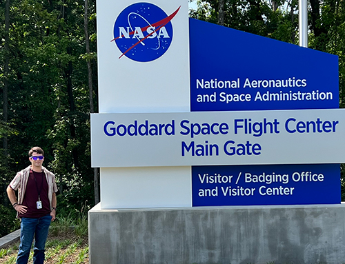 Tyler Robbins, who is pursuing an astrophysics degree with a minor in mathematics, expanded his research experience and knowledge at NASA's Goddard Space Flight Center in Greenbelt, Maryland. He is posing in front of a NASA sign.