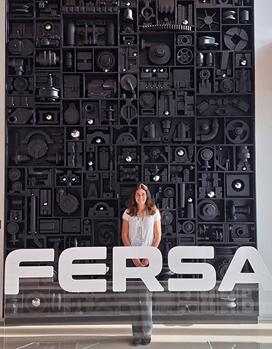 Elise Essenmacher, a junior mechanical engineering student, poses in front of a Fersa sign at the company's headquarters in Zaragoza, Spain. 