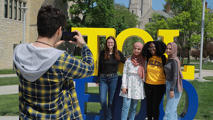 A group of UToledo students pose for a photo in front of the TOL-EDO sign on Main Campus.