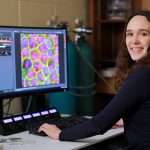 Sophia Durham poses at a computer in the research lab of Dr. Rafael Garcia-Mata, a professor who explores the mechanisms of cell behavior in the Department of Biological Sciences.