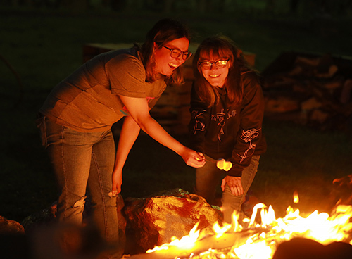 Leslie Sacoto, left, a biology student, and Danielle Hasting, a media communication student, roast marshmallows at the bonfire.