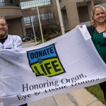 Chandler Smith, a surgical intensive care unit nurse at The University of Toledo Medical Center, and Megan Charette, a clinical research nurse in the UTMC Department of Urology and Transplantation hoisted the Donate Life flag outside UTMC on Wednesday to mark National Donate Life Month.