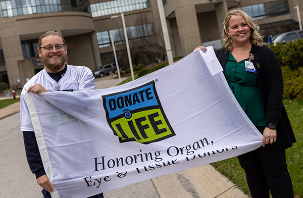 Chandler Smith, a surgical intensive care unit nurse at The University of Toledo Medical Center, and Megan Charette, a clinical research nurse in the UTMC Department of Urology and Transplantation hoisted the Donate Life flag outside UTMC on Wednesday to mark National Donate Life Month.