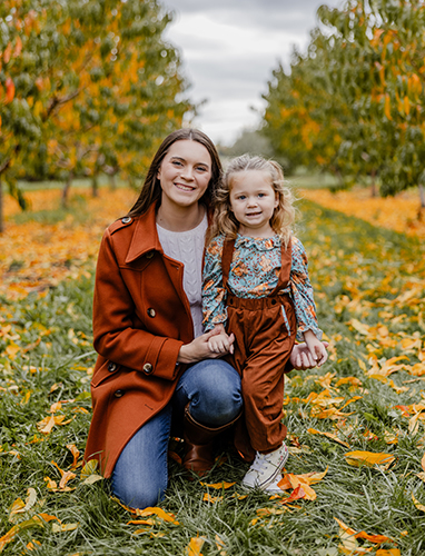 Portrait of Anna Venis and her young daughter outside during the fall. 