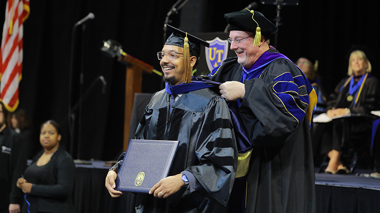 Anthony Goodwin, who completed his Ph.D. in Health Education, is hooded by Dr. Tim Jordan, a professor in the Department of Population Health in the College of Health and Human Services, during the May 3 graduate commencement and doctoral hooding ceremony in Savage Arena.