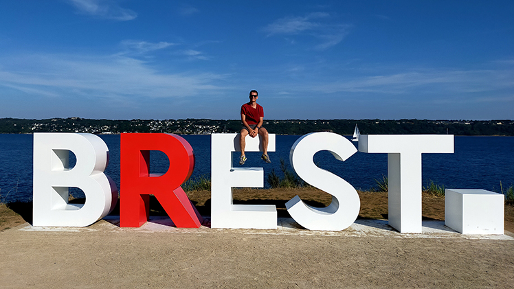 Tim Cullaz sits on a sign for ithe École Nationale d'Ingénieurs de Brest in his home country of France.