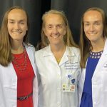 Identical twin sisters, Lyndsey Matus, left, and Alex Best, who recently completed medical school together at UToledo, pose with their mom, Dr. Coral Matus, a doctor at UTMC.