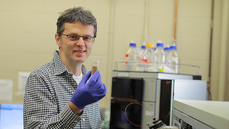 Portrait of Dr. Dragan Isailovic, professor in the Department of Chemistry and Biochemistry, holding a vial in a research lab.