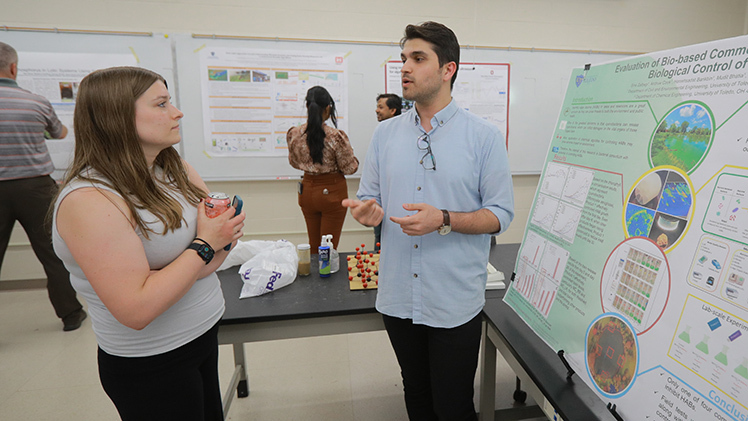 Ashleigh Boss, a biological scientist for the U.S. Army Corps of Engineers, listens as Sina Zalbegi, a doctoral candidate in civil engineering at The University of Toledo, explains his team’s research to identify bacterial-based products for controlling harmful algae blooms.