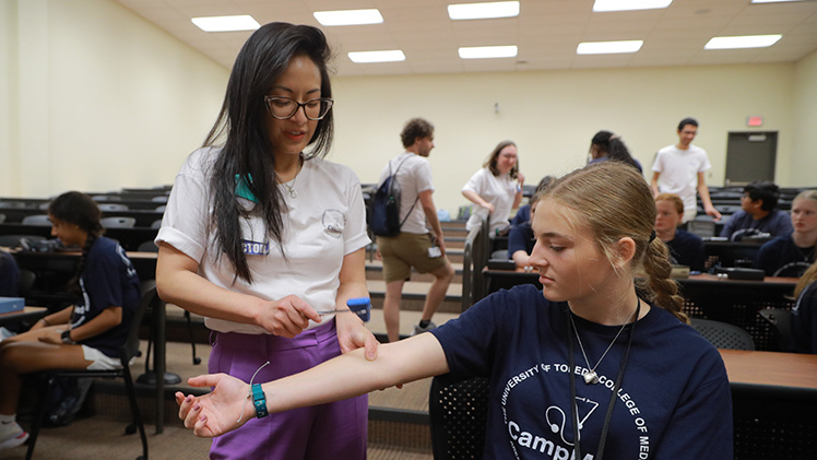 Dr. Luisa Corpuz, an assistant professor of Family Medicine and medical director of the Physician Assistant Studies at the College of Medicine and Life Sciences, tests the reflexes of Caite Wixom, one of 26 area high school students participating in CampMed last Thursday and Friday on Health Science Campus.