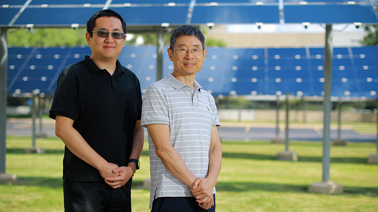 Outside portrait of, from left, Dr. Zhaoning Song, a research professor at UToledo, and Dr. Yanfa Yan, a Distinguished University Professor in the Department of Physics and Astronomy, who are posing in front of a solar array on Main Campus.