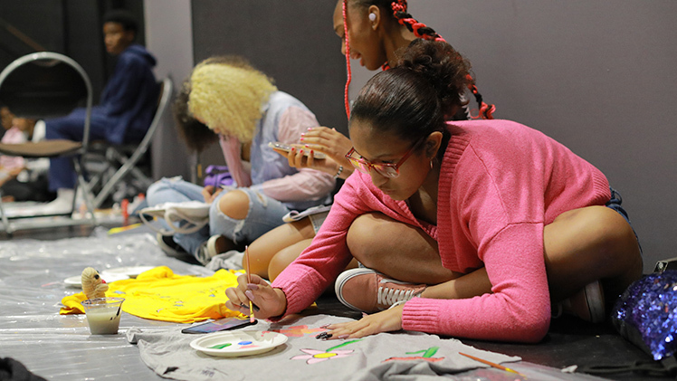 Peyton Sawyer (Toledo School for the Arts, 10th grade) paints flowers on a t-shirt at the Toledo Excel Art Project.