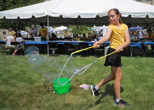 Anastasia Glassman, 10, from Toledo, blows giant bubbles outside the kids tent.