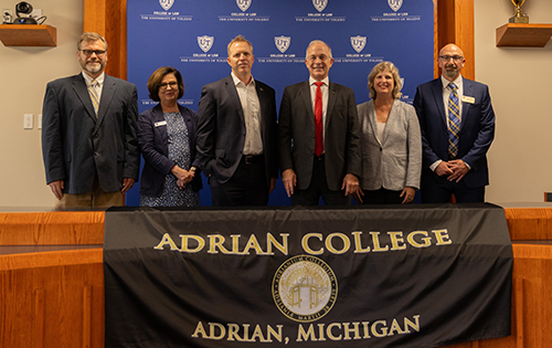 UToledo and Adrian College representatives formalize a joint degree agreement on Wednesday, July 24. From left are Nathan Goetting, professor and director of the Romney Institute for Law and Public Policy at Adrian College; Rebecca Zietlow, interim dean of the UToledo College of Law; Matt Schroeder, interim president of UToledo; Dr. Jeffrey Docking, president of Adrian College; Dr. Andrea Milner, vice president and dean of academic affairs at Adrian College; and Dr. Antonis Coumoundouros, dean of graduate studies and continuing education at Adrian College.