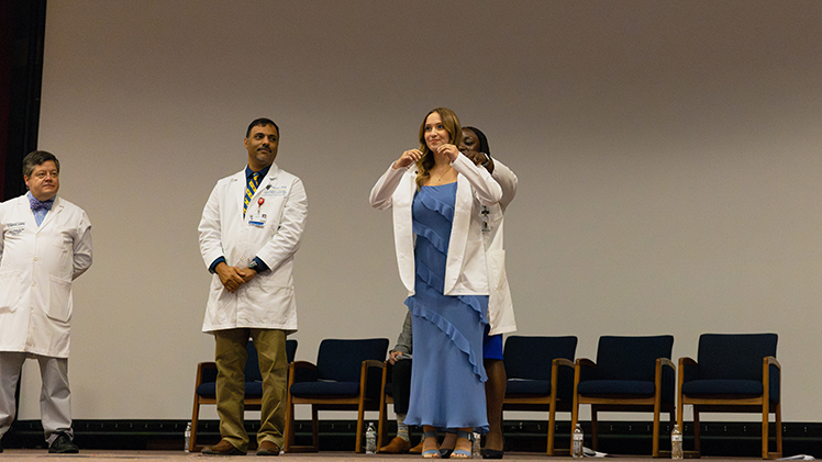 Holly Heck, a first-year medical student at The University of Toledo, receives her white coat during the College of Medicine and Life Sciences white coat ceremony on Friday, July 19, in Nitschke Hall.