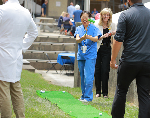 Zhihua Huynh, a staff nurse in pre-op testing at The University of Toledo Medical Center, laughs after missing a putt during Thursday’s Employee Appreciation Summerfest 2024 at Health Science Campus. The event featured a free meal, games, raffle prizes, music and a photo booth.