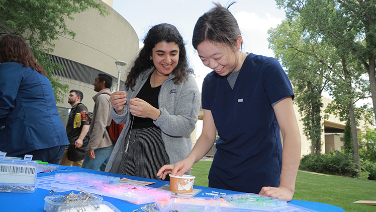 Saira Khan, left, and Anna Guo, both fourth-year medical students, make custom bracelets at Employee Appreciation Summerfest 2024 on Thursday at Health Science Campus.