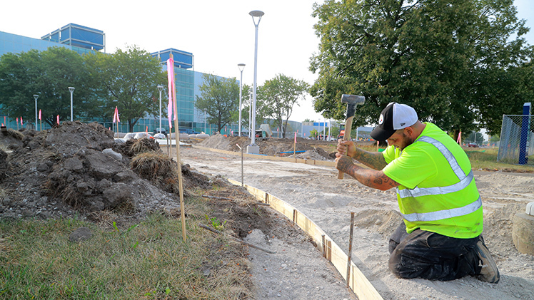 Octavio Delao, a worker with the Spieker Company, pounds a stake for a concrete form Thursday morning on the new academic quadrangle on The University of Toledo’s engineering campus following the removal of Palmer Hall in July.