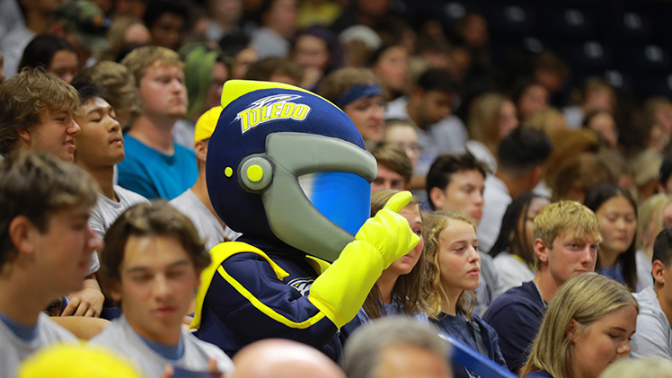 Photo of UToledo mascot Rocky in a crowd of students inside Savage Arena.