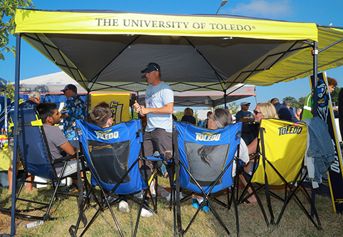 A UToledo tent with Rocket fans sitting in chairs during pre-game festivities.