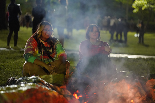 Two female students laugh in front of the bonfire during Rocket Welcome Weekend.