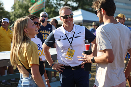 Interim President Matt Schroeder talks with 3 students during pre-game festivities.