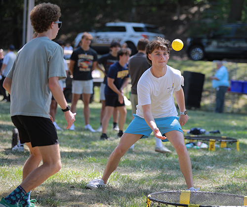 2 male students play a game during the class of 2024 barbecue on the Flatlands.