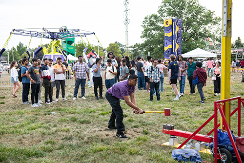 A male student tries to ring the bell with the hammer game at the annual CAP Carnival at Carter Field as part of the 2024 Rocket Welcome Weekend.