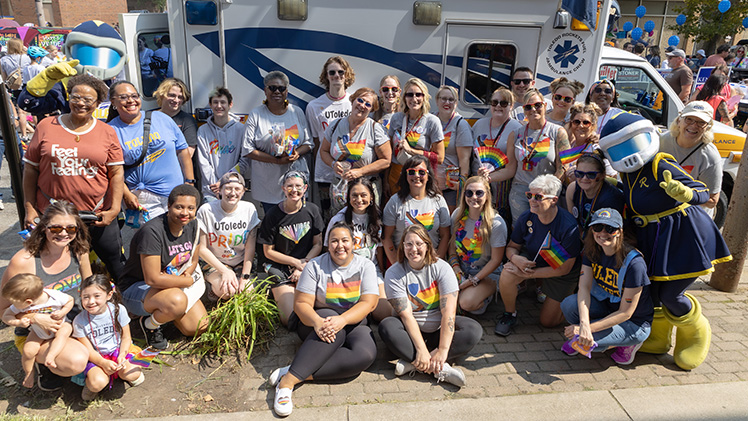 UToledo students, staff, faculty, alumni and family members along with Rocky and Rocksy pose for a photo at the Toledo Pride parade in downtown Toledo celebrating the LGBTQIA+ community.