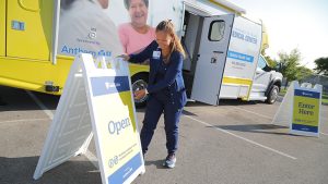 Kim Steele, lead nurse for the UToledo Health mobile health unit, sets up an 'open' sign outside the mobile clinic ahead of a screening unit. 