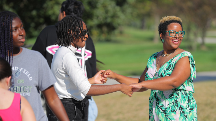 Damian Cosby, a sophomore studying biology, and Taryn Jefferson, a junior studying criminal justice, learn beginner-level Hispanic dances Monday with other students during Bailando con APsi at Centennial Mall.