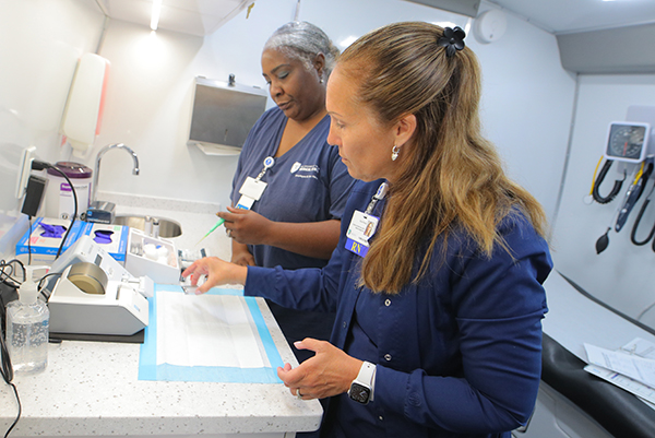 Kim Steele, right, the lead nurse for UToledo Health’s mobile health, and licensed practical nurse Gloria Johnson prepare testing equipment before seeing patients in the UToledo Health mobile health unit outside the Mott branch library. 