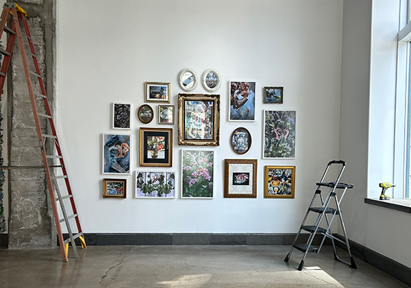 An art installation by Brian Carpenter, a senior lecturer in UToledo’s Department of Art, with artwork hanging on a wall with a ladder and drill also in the photo.