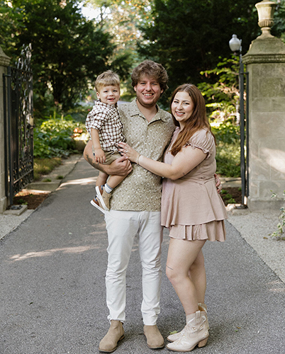 Portrait of Hayden Grady, a biology sophomore, left, and Christie Hoeflinger, a health sciences junior. Hayden is holding the couple's infant son. 