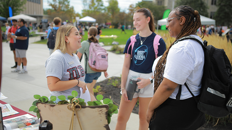 Three students gather at a event on UToledo's Centennial Mall.