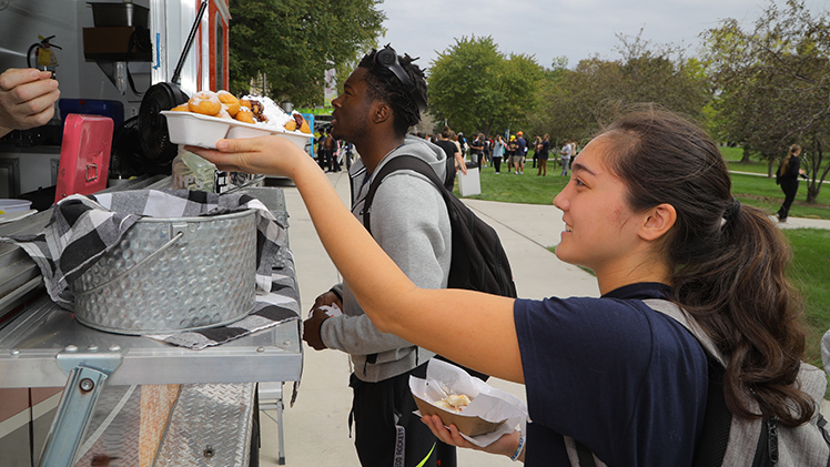 Morgan Kay, a freshman biochemistry student, takes her order of fresh donuts from a vendor during Tuesday’s annual Eat the Streets event, which brought food trucks and inflatables to Centennial Mall as part of a weeklong Homecoming celebration leading up to Saturday’s game.