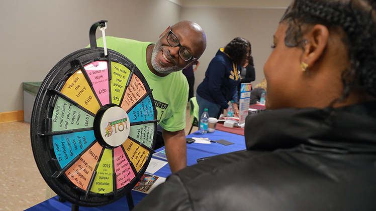 Craig Turner, program manager for the Business Career Programs Office in the John B. and Lillian E. Neff College of Business and Innovation, spins a wheel to simulate unexpected expenses financial during Finances 101, an interactive game designed to teach local high school students about financial literacy.