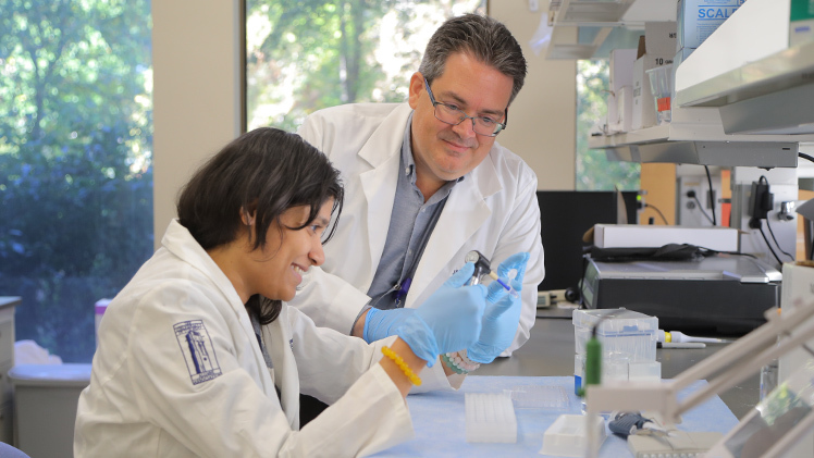 Feature photo of Dr. James Burkett, an assistant professor of neuroscience, and N.J. Saferin, a Ph.D. Student in neuroscience, working in a research lab.