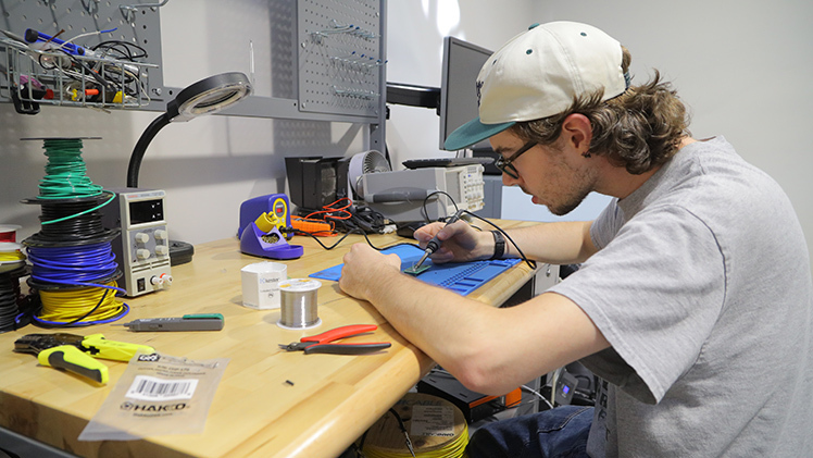 Ethan Richey, an electrical engineering technology junior and treasurer of the Maker Society, solders on an electrical circuit board in the Paul A. Hotmer Maker Space.