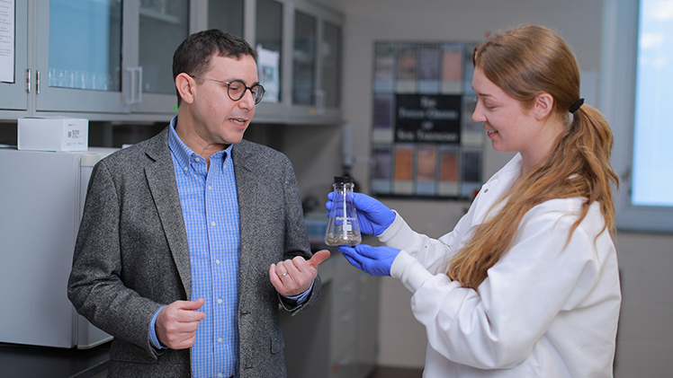 Feature portrait of Emma Campbell, a full-time laboratory and field technician, and Dr. Michael Weintraub, a soil ecologist and professor in the Department of Environmental Studies, work together in a research lab.