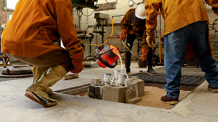 Artists forge a bronze medallion inside the foundry in UToledo’s Center for Sculptural Studies. Photo: Toledo Museum of Art.