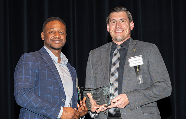 Photo of Adam Motycka, on the right, assistant general counsel at The University of Toledo, holding his award for being recognized as on Toledo's 2024 “20 Under 40” list.