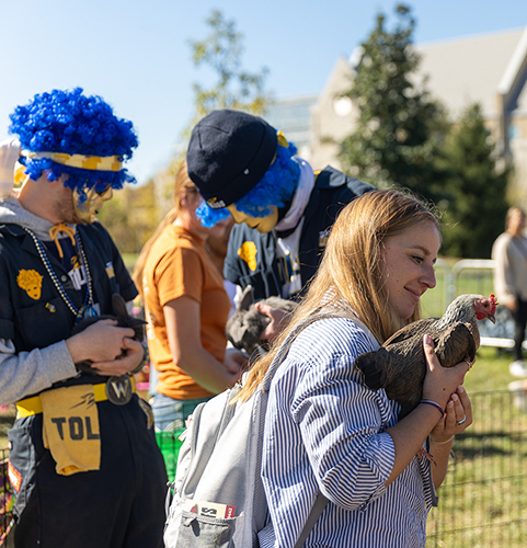 Female UToledo student holds a chicken at Wednesday’s CAP Petting Zoo on Memorial Field House lawn. 